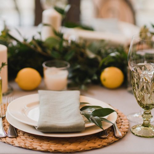 Coziness and style. Modern event design. Table setting at wedding reception. Floral compositions with beautiful flowers and greenery, candles, laying and plates on decorated table.